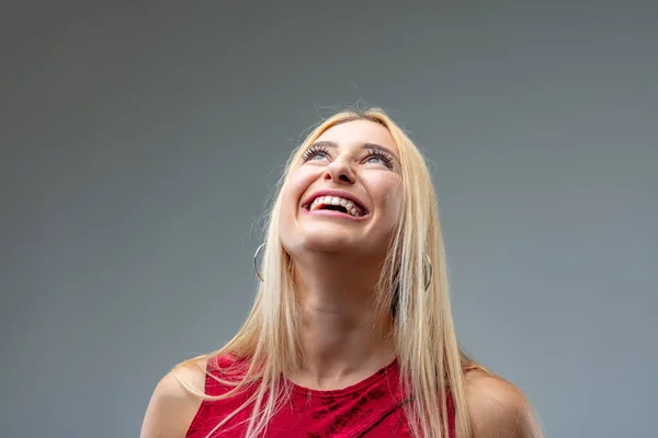 frontal portrait of young blond woman in deep red dress ; gradually laughing more and more as she looks up and bends her head back and is overjoyed