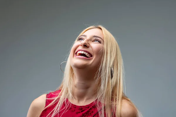 frontal portrait of young blond woman in deep red dress ; gradually laughing more and more as she looks up and bends her head back and is overjoyed