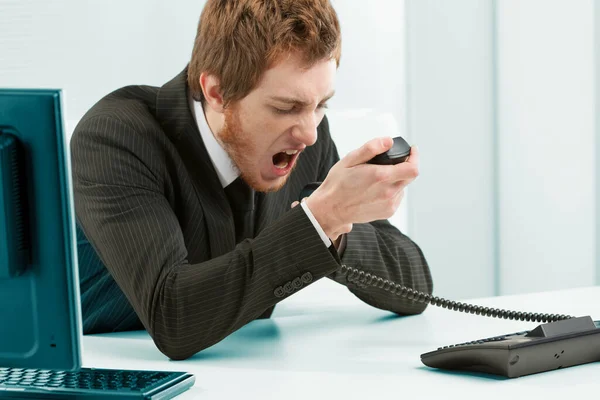 可能有必要控制工作环境中的攻击行为 办公室里穿着西装的人紧紧抓住话筒 怒气冲冲地大叫 对着电话大喊大叫 — 图库照片