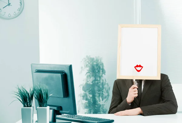 Man with framed sign head in an office, also places a female lip shape with red lipstick in front of the available white space.