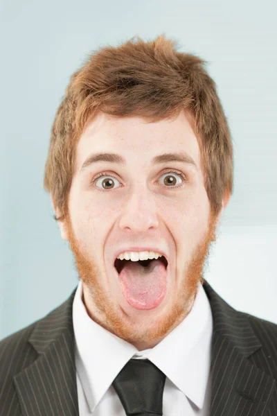 短い赤い髪とひげを持つ若い男のクローズアップ正面の肖像画 目と口を開いて 舌を開いて 笑顔の人とクレイジーな表現 — ストック写真