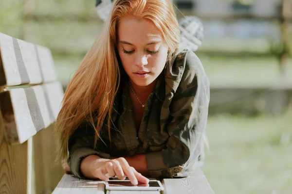 캐주얼 복장의 아름다운 소녀는 벤치에 인터넷을 사용하거나 공부를 하거나 하거나 — 스톡 사진