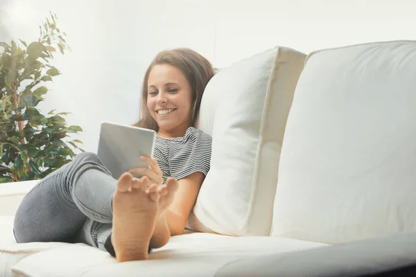 Jovem Sentada Sofá Usando Seu Tablet Digital Relaxada Com Pernas — Fotografia de Stock