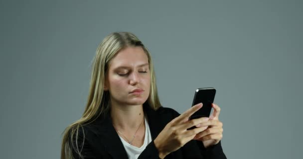 若いブロンドの女性は喜んで突然接続やモバイルが動作を停止したときに彼女のスマートフォンを使用しています 彼女はフラストレーションを感じて腹を立てて全てを壊したがってる — ストック動画