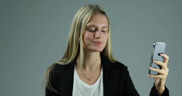 Mujer Rubia Joven Utiliza Teléfono Inteligente Contra Fondo Neutro Silencio — Vídeos de Stock