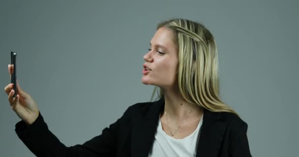 Mujer Rubia Joven Utiliza Teléfono Inteligente Contra Fondo Neutro Silencio — Vídeo de stock