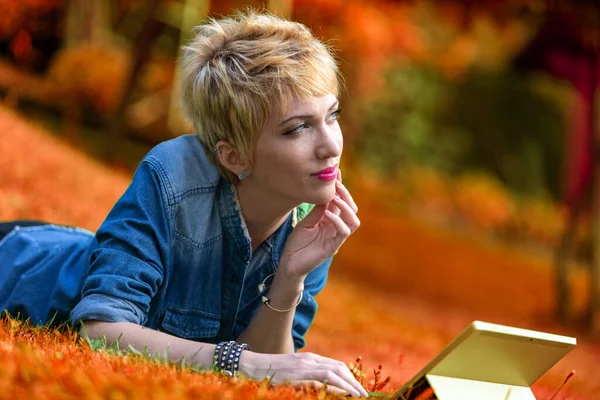 一个年轻女子脸朝下躺在草地上 同时使用笔记本电脑平板组合的多彩的肖像 在自然和富裕的环境中 她能够想象这将持续多久 — 图库照片