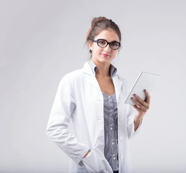白いラボのコートとメガネを身に着けている女性は デジタルタブレットを保持し 視聴者を直接見ています 彼女は医療科学の専門家 技術専門家 またはデータ分析者ですか 彼女は生物学者ですか — ストック写真