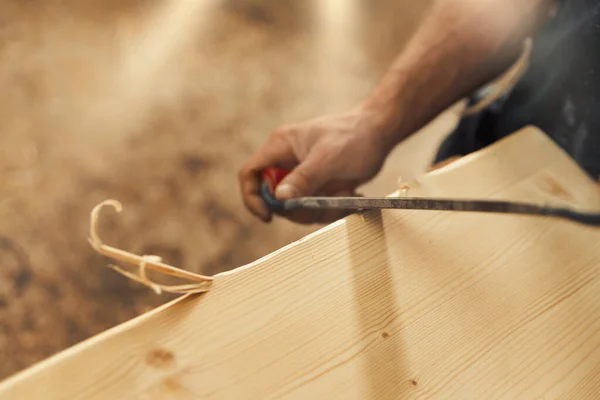 工匠们用小刀在家具的木制板的边缘上雕刻和装饰 可见强壮的男性手和木头 体现了木匠的本质 — 图库照片
