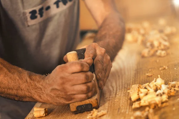 大工として知られる堅実で強い男である木工職人は 板を伝統的な方法で平面化し 金色の木のカールのように見えるおがくずの削り屑を作り出します それは骨の折れる — ストック写真