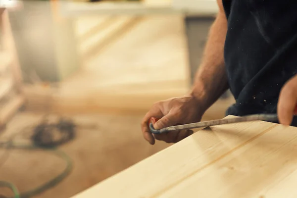 職人は ドローナイフで家具を構成する木製の板の端を彫刻し 面取りします 強い男性の手と木が見え 大工の本質を体現しています — ストック写真