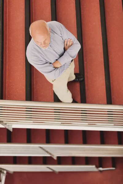 Літній Чоловік Складеними Руками Зверху Він Стоїть Червоно Кольорових Сходах — стокове фото