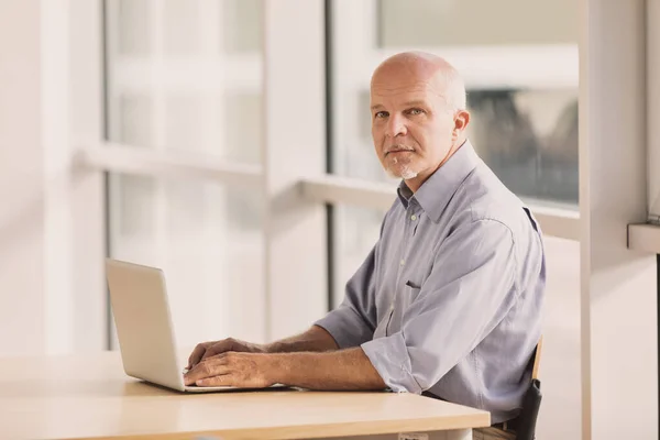 Oudere Man Gebruikt Een Laptop Een Helder Modern Bedrijfsklimaat Hij — Stockfoto
