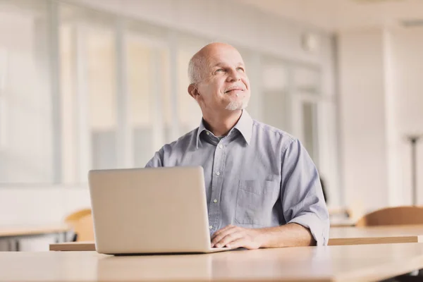 Starší Muž Laptopem Moderní Společenské Hale Přimhouří Oči Pousmáním Dívá — Stock fotografie