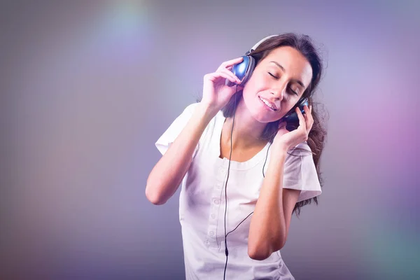 Blue headphones-clad girl dances, sings to music amidst dazzling, fast-paced party lights. Evident joy, happiness, and amusement on the face of slim, long-haired young lady