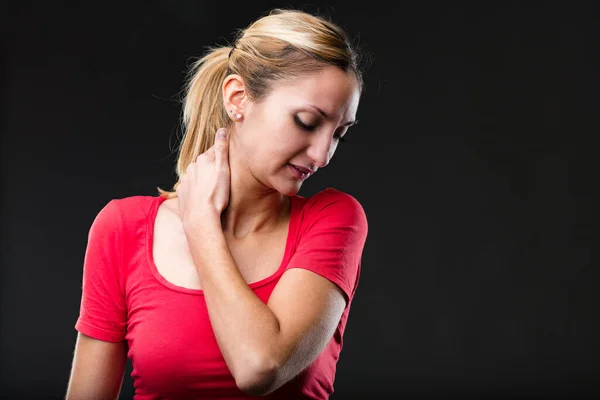 Neck pain: woman in red shirt shows discomfort, facial grimaces. Tired and fed up, suffering from back pain, cervical, and head strains. Close-up portrait, faded black background