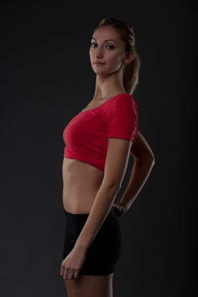 女性の体の調子を合わせなさい ジムワークアウトは決定 責任を反映します 赤シャツ フラット腹 黒のショートパンツのブロンドの女の子の肖像 — ストック写真