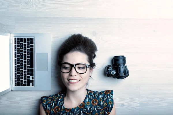 Young woman with glasses, laptop, and camera. Photographer, artist, journalist, vlogger, or communication expert with copyspace
