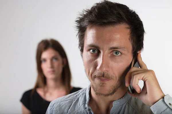 Foreground Man Smartphone Call Suspicious Woman Blurred Background Betrayal Jealousy — Stock Photo, Image