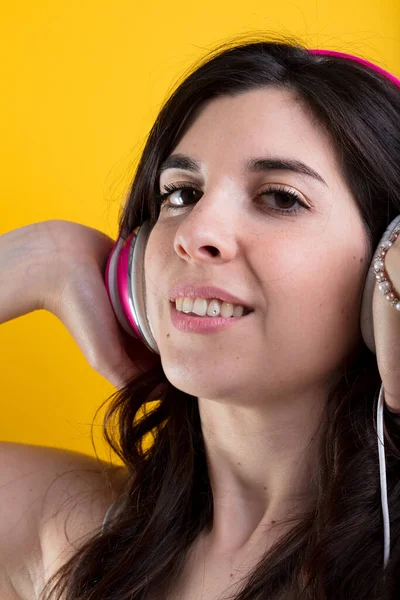 真剣に音楽を愛する女性はピンクのヘッドフォンをし 微笑んで 物語の没入型サウンドを楽しんでいます — ストック写真