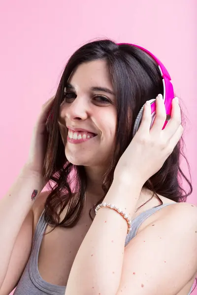 微笑的女人 沉浸在音乐中 用粉色耳机讲故事 在五彩斑斓的背景下跳舞 — 图库照片