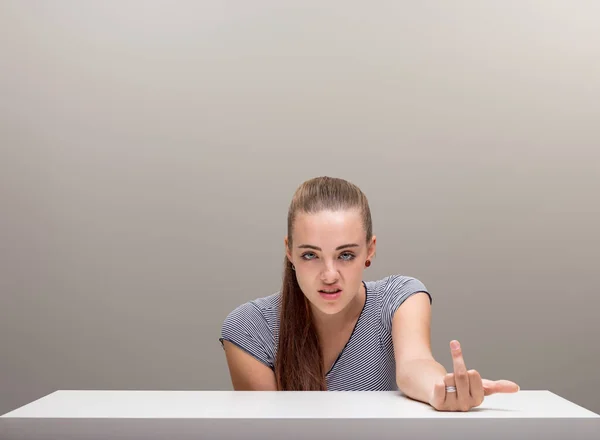 Schöne Mädchen Sitzt Einem Tisch Neutraler Hintergrund Zeigt Ihren Mittelfinger — Stockfoto