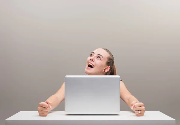 美しい若い女性は 彼女のラップトップでテーブルに座って 彼女の顔は コピースペースに上向きになって 過度の喜びと満足感を表現しています コンピュータ インターネット ポジティビティ — ストック写真
