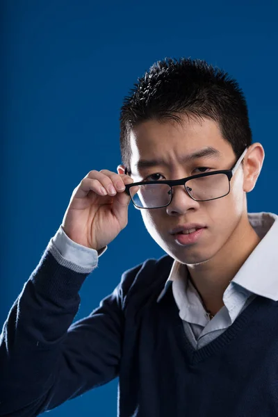 An Asian man lowering glasses, skeptical expression suggesting, \'What\'re you saying? I don\'t agree, nor do I appreciate your tone!\'. Struck and surprised negatively