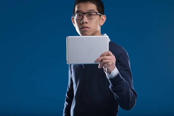 一个亚洲人在平板电脑上查看新闻 在蓝色的背景下停下来看了看 戴眼镜 他对屏幕上显示的内容感兴趣 电子邮件或安全镜头 — 图库照片