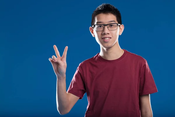 Jonge Aziatische Man Met Bril Maakt Een Overwinning Teken Glimlacht — Stockfoto