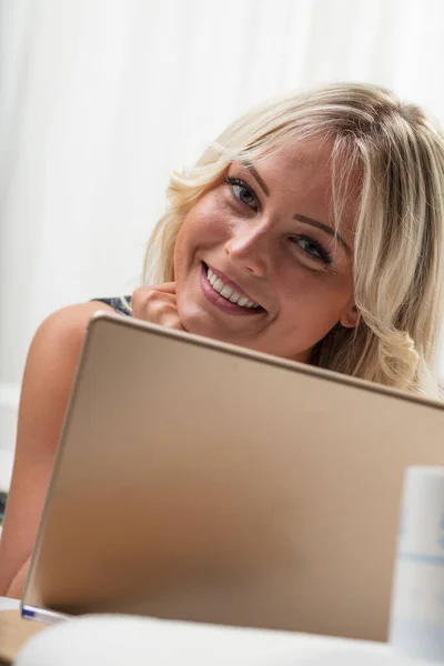 快乐的金发女人躺在沙发上 带着平板电脑 热情地微笑着 她是在购物 看电视剧还是看社交媒体视频 — 图库照片