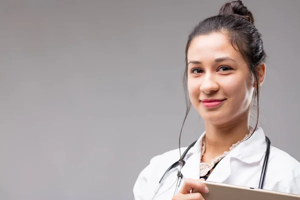 Head and shoulder shot of a lovely Filipino doctor, she smiles reassuringly with her digital tablet. It\'s a tool enhancing surgeon and diagnostician skills with instant communication and data access