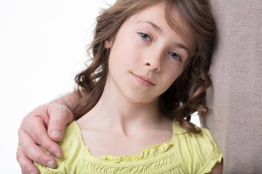 A curly-haired girl in green leans on her father, trusting in his loving support clipart