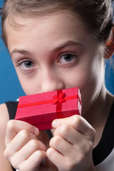 赤い贈り物を保持するエレガントな女の子の肖像画 予想と驚きとともに輝く — ストック写真