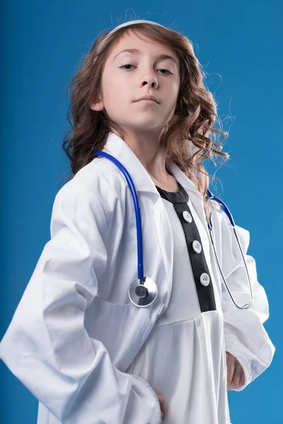 Modrém Pozadí Dívka Lékařském Oblečení Stetoskopem Pózuje Hrdě Zná Prestiž — Stock fotografie
