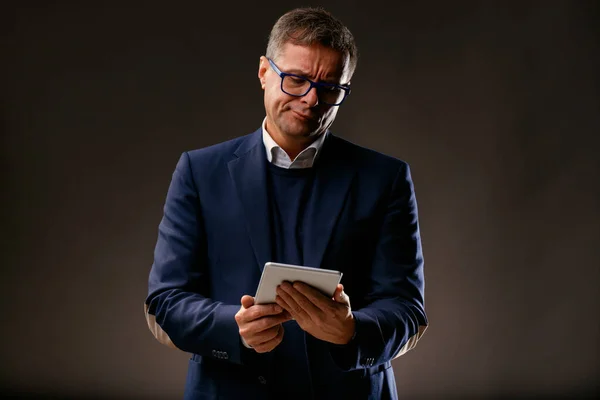 Zarif Orta Yaşlı Bir Adam Tablet Ekranına Bakarken Şüphecilik Gösteriyor — Stok fotoğraf