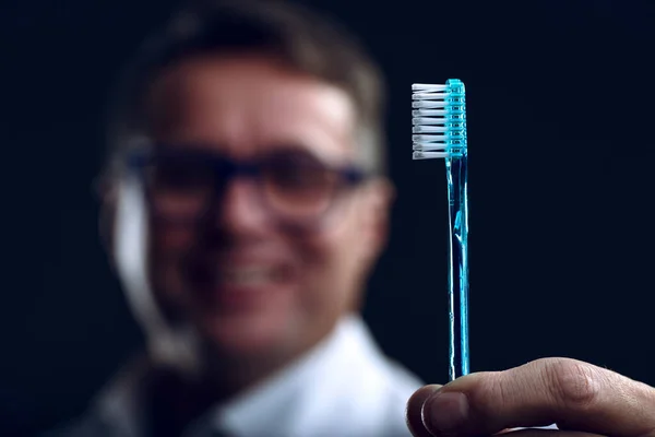 Arka Planda Bulanık Bir Dişçinin Tuttuğu Mavi Diş Fırçasının Yakın — Stok fotoğraf