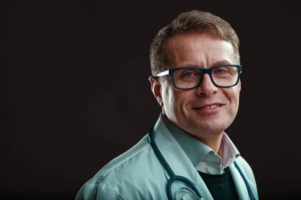 一位戴着眼镜的中年医生 完全放松 热爱自己的职业 彬彬有礼 乐于帮助人们度过难关 黑暗背景下的肖像 — 图库照片