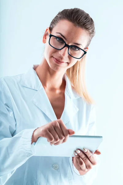 一位技术专家 穿着白色实验室外套 头戴平板电脑的快乐女人 她提倡关键利用技术进行数据分析和验证 同时鼓励通过应用程序和实习生分享知识 — 图库照片