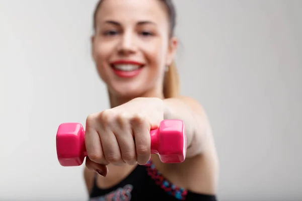 背景上模糊的女人有聚焦的小粉色的重量 她喜欢轻松的体操锻炼 这在她的生活中提高了她的快乐和积极的一面 — 图库照片