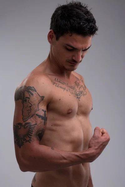 Shirtless Muskulös Man Flexar Och Observerar Sin Tatuerade Biceps Tatueringarna — Stockfoto