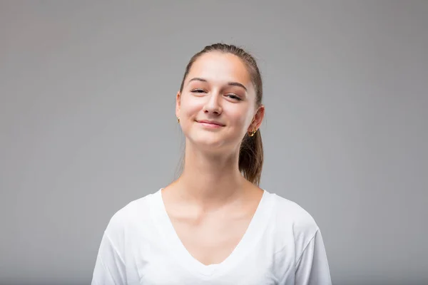 Frontal portrait of young woman with a special smiling expression: she knows you are wrong but welcomes your humanity with acceptance or tolerance.