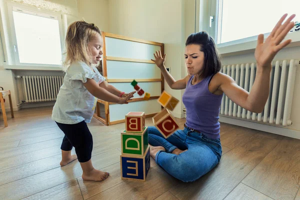 Blonde daughter and mother enjoy playtime with wooden toys in the bedroom, growing together in fun and educational bonding