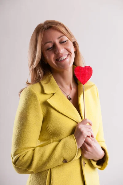 Mujer Adulta Sonriente Soñadora Con Abrigo Amarillo Sujeta Firmemente Símbolo — Foto de Stock