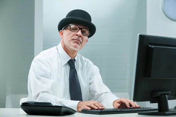 Stereotypical Modern Office Man Types His Computer Wearing Glasses Bowler — Stock Photo, Image