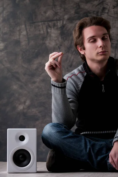 Young Man Black Grey Sweater Sits Cross Legged White Speakers — Stock Photo, Image