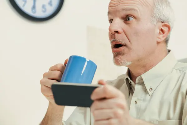 Ein Älterer Mann Seiner Küche Blickt Erstaunt Auf Ein Smartphone — Stockfoto
