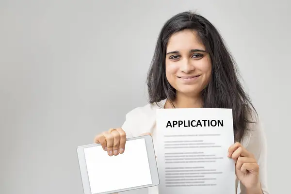 这位印度女士留着一头光滑的黑发 同时展示了申请表和平板电脑 这标志着传统方法和现代方法的结合 她穿着一件米黄色的衬衫 暗示着她的效率 — 图库照片