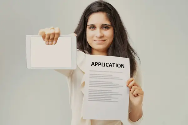 这位有着一头乌黑长发和米色衬衫的年轻印度女性 拿着一个带有空白屏幕的应用程序和平板电脑 强调了科技在求职和官僚工作中的价值 — 图库照片