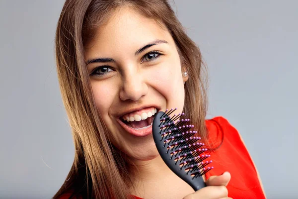 Exuberant singing session captured, with a common hairbrush turned prop. Woman with hairbrush